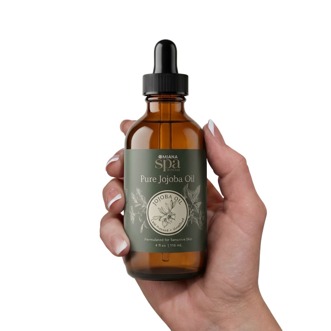 Hand holding a bottle of Omama Spa Pure Jojoba Oil on a white background